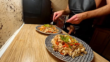 A bare-chested gay chef preps chicken and vegetable rice noodles